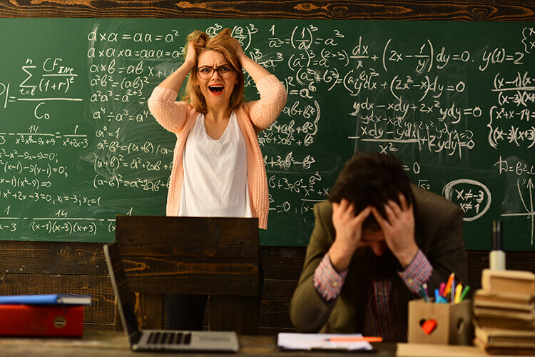 man and woman teacher in classroom, both with hands in their hair with frustration